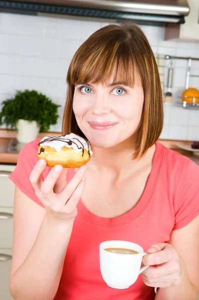 Молодая женщина наслаждается чашкой кофе и пончиком — стоковое фото