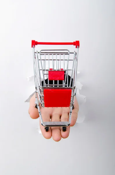 Carrinho de compras através de buraco no papel — Fotografia de Stock