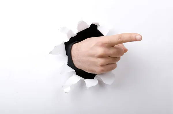Hand through the hole in paper — Stock Photo, Image