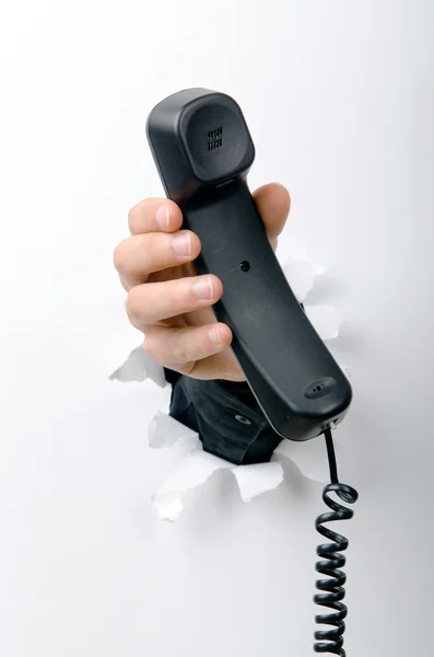 Hand som håller telefonen genom hål i papper — Stockfoto