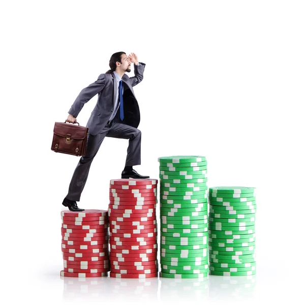 Stacks of casino chips and climbing businessman — Stock Photo, Image