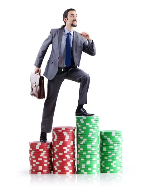Stacks of casino chips and climbing businessman — Stock Photo, Image