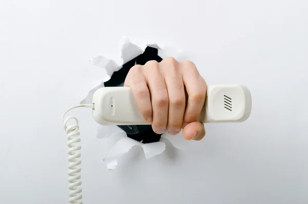 Mano sosteniendo el teléfono a través del agujero en papel — Foto de Stock