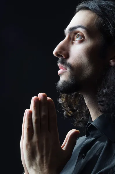 Young man praying in darkness — Stock Photo, Image