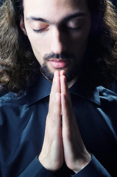 Молодий чоловік молиться в темряві — стокове фото