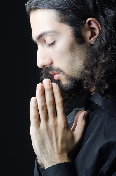 Young man praying in darkness — Stock Photo, Image