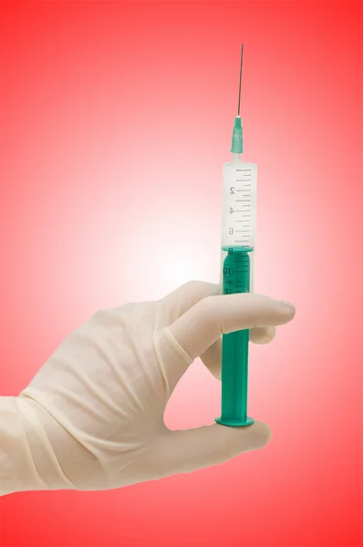 Hand holding syringe on gradient — Stock Photo, Image
