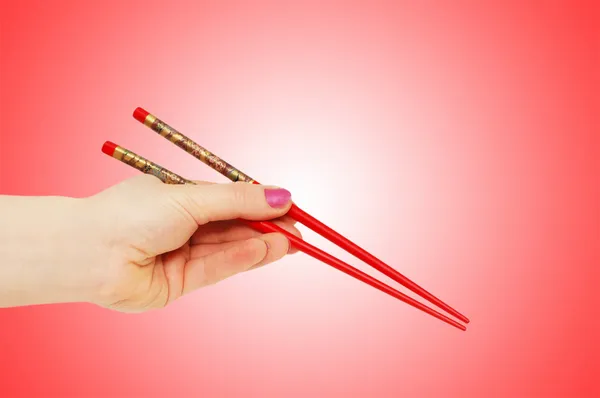 Mão segurando choipsticks no gradiente — Fotografia de Stock