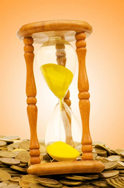Время - денежная концепция - песочные часы и монеты — стоковое фото