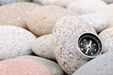 Navigation compass on stone pebbles clipart