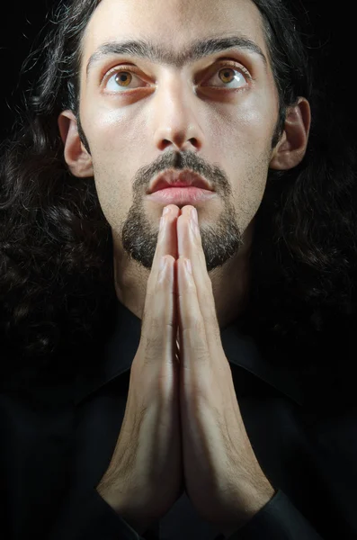 Young man praying in darkness — Stock Photo, Image