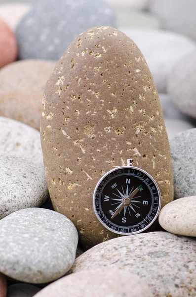 Навигационный компас на каменной гальке — стоковое фото