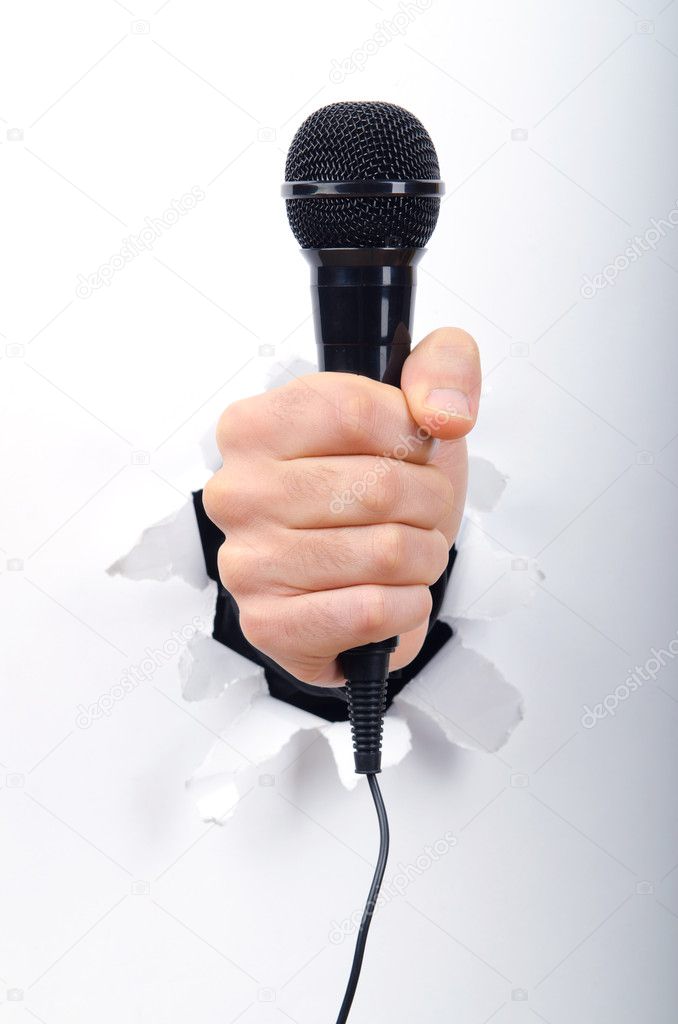 Hand holding microphone through hole in paper