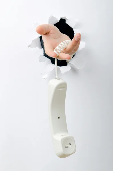 Рука держит телефон через отверстие в бумаге — стоковое фото