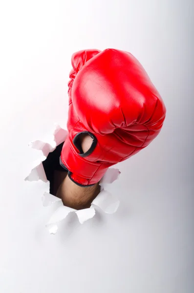 Hand i boxning handske genom papper hål — Stockfoto
