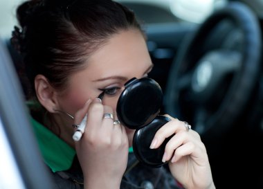 The girl is doing makeup in the car clipart