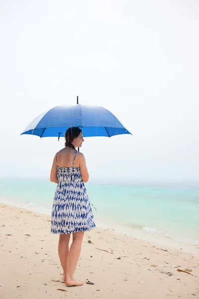 Женщина на пляже под дождем — стоковое фото