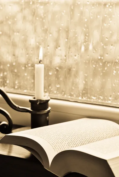 Een boek en een kaars op een regenachtige dag - sepia — Stockfoto