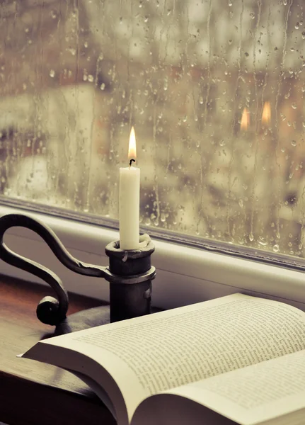 Ein Buch und eine Kerze an einem regnerischen Tag Stockbild