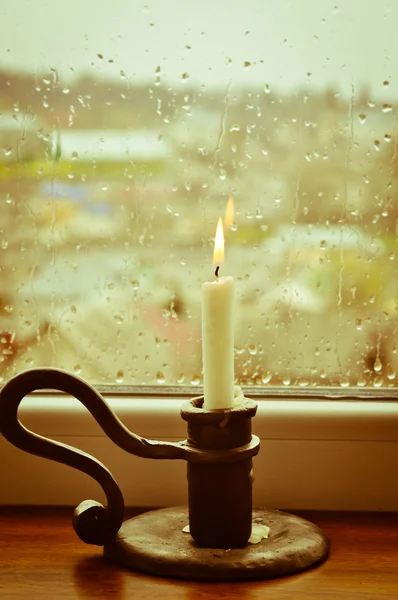 Ein stilisiertes Bild einer brennenden Kerze an einem regnerischen Tag Stockbild