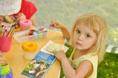 ZBARAZH, UKRAINE – MAY 6: Unidentified girl painting on the street during Tourist season opening festival in Zbarazh Castle on May 6, 2012 in Zbarazh, Ukraine. clipart