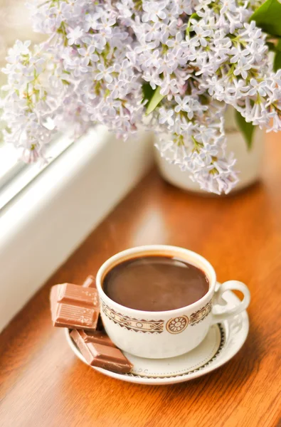 stock image Ceramic cup with coffeeб chocolate and bouquet of lilac