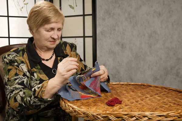 Old woman with a needle and a thread — Stock Photo, Image