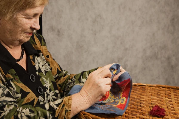 Oude vrouw met een naald en een draad — Stockfoto