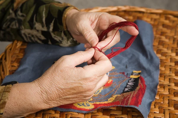 Old woman hand embroiders with a thread — Stock Photo, Image