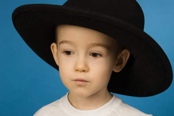 Barnet i en stor svart hatt — Stockfoto