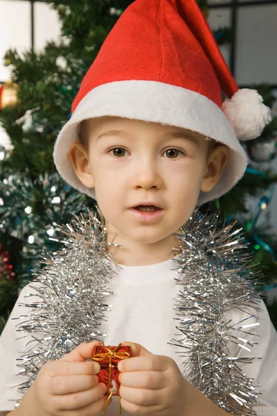 Boy wearing santa claus clothes with a new year gift — Stock Photo, Image