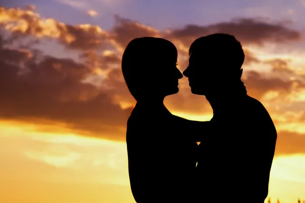 Silhouette d'un jeune couple avec le coucher de soleil derrière eux — Photo