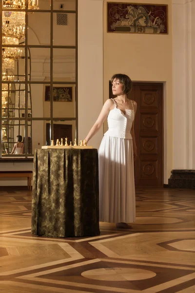 Ung kvinna spela schack i den rika interiören — Stockfoto