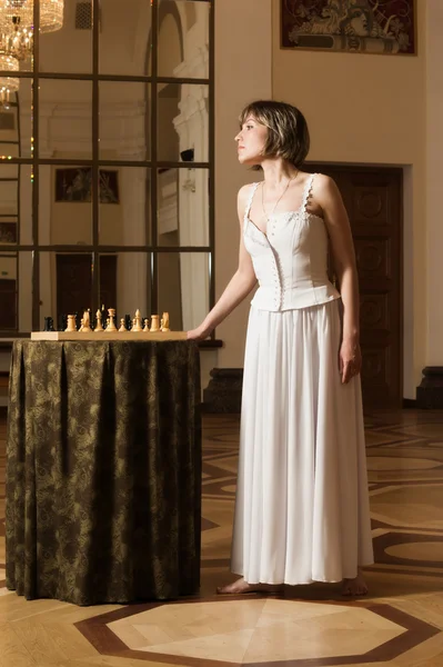 若い女性は豊かなインテリアでチェスをプレイします。 — ストック写真