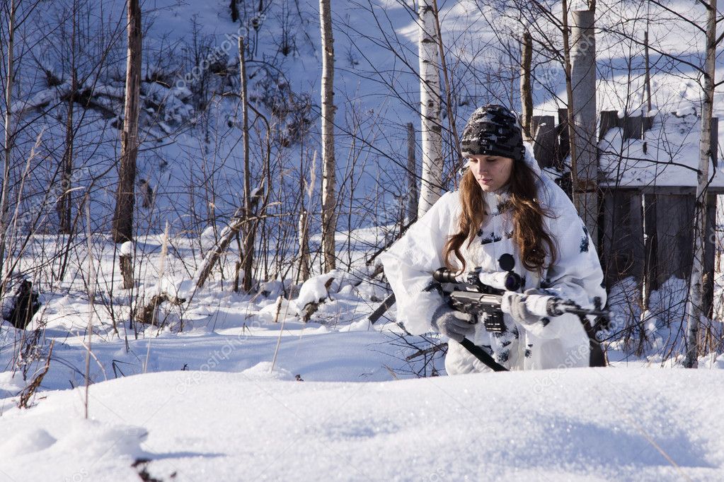 Sniper girl in white camouflage at winter forest.
