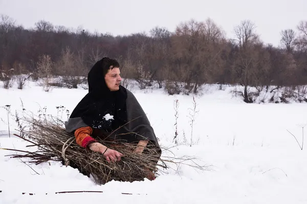 Contadino medievale con un fascio di legna seduto sulla neve — Foto Stock