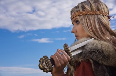 Viking girl warrior on a blue sky background clipart