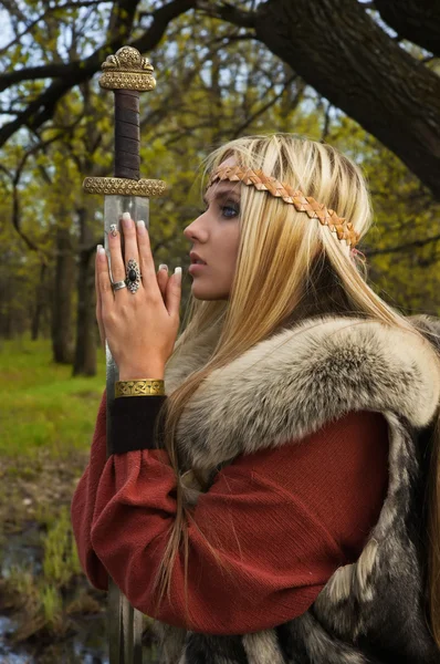 Chica vikinga con espada en un bosque — Foto de Stock