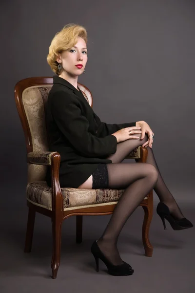 Vacker kvinna i en i en business suit sitter i en fåtölj — Stockfoto