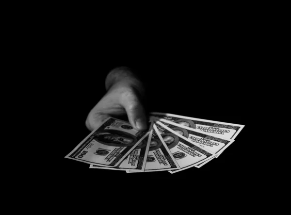 Рука с долларами над черным — стоковое фото