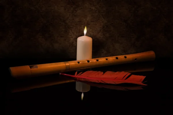 Zátiší s flétnu, svíčka a červené pírko — Stock fotografie