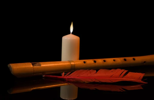 Naturaleza muerta con flauta, vela y pluma roja — Foto de Stock