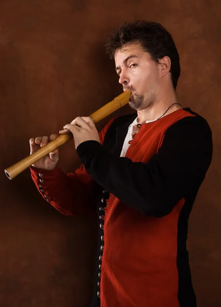 Человек в средневековом костюме играет на флейте — стоковое фото