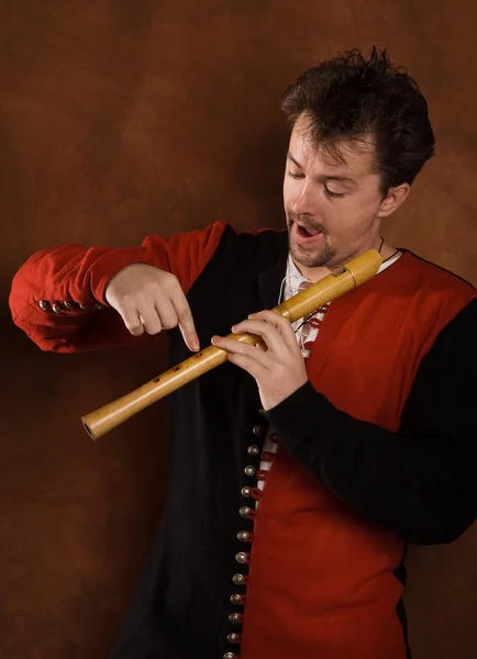 Человек в средневековом костюме играет на флейте — стоковое фото