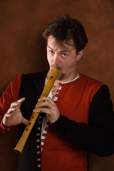 Man in a medieval suit plays a flute — Stock Photo, Image