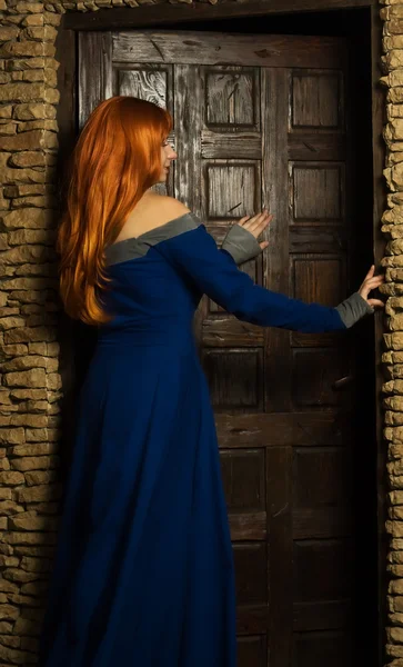 文艺复兴时期的衣服打开门的年轻女人 — 图库照片