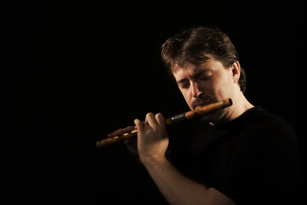 Mannen i svart spelar en flöjt — Stockfoto