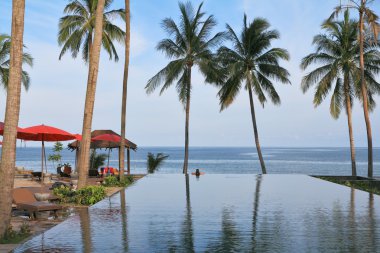 Beach pavilion with red roofs, palm trees clipart