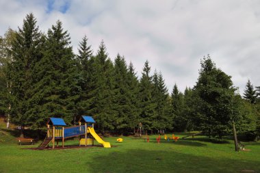 Park for children at the forest resort in the Alps clipart