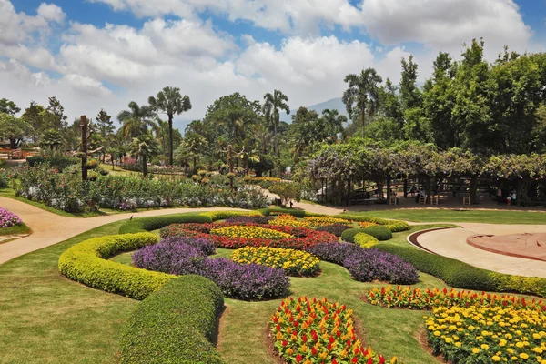 Prachtvolle Blumenbeete, grüne Rasenflächen und tropische Bäume — Stockfoto